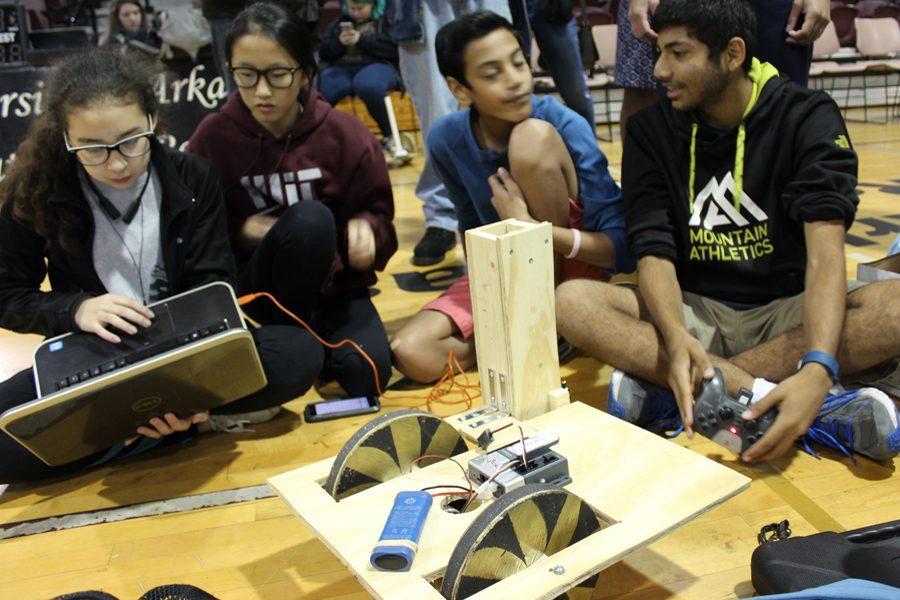 Building team members Alida Kaufmann, Anne Li, Akshat Shah, and Dhruv Modi discuss future modifications to their robot.