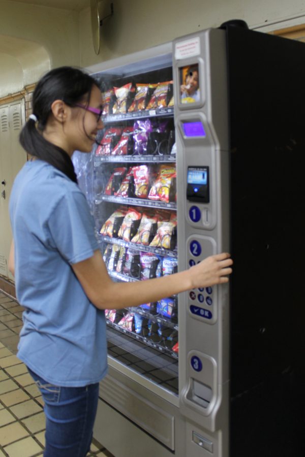 Senior Evalyn Berleant tries out a vending machine for a mid-day snack.