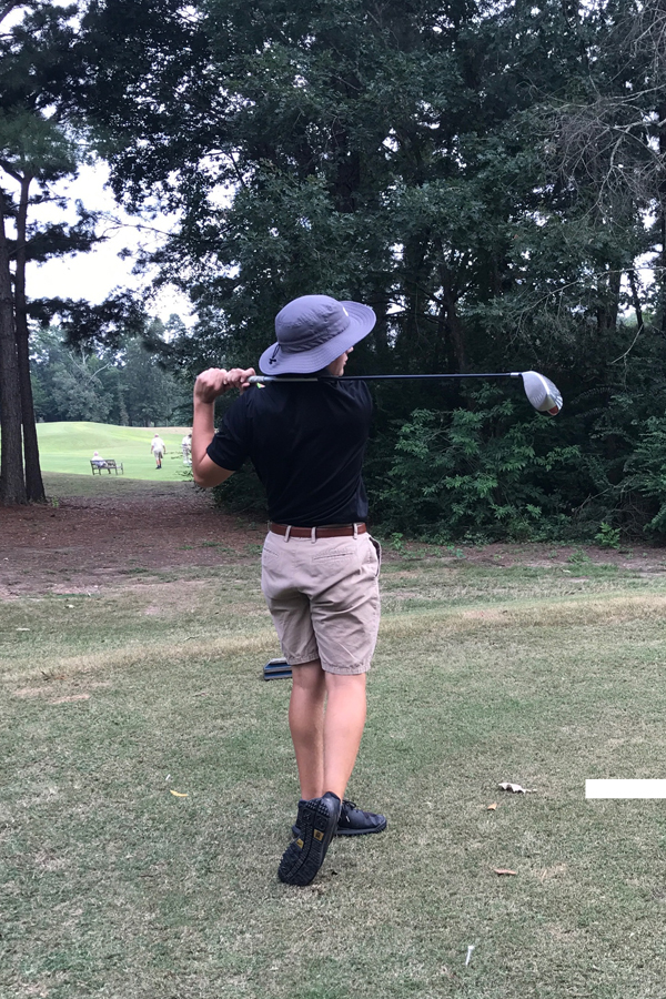 Senior Will Thompson takes a swing on the golf course. 