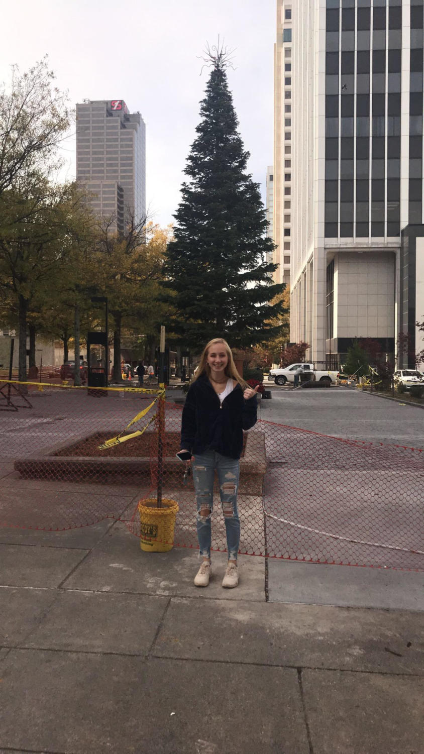 Junior Julia Greenfield stands in front of the 45’ foot Christmas tree the day it was put up. Even though it wasn't the promised 65’ foot tree, it still brings in the holiday spirit with the lights and decorations. (Photo by Emily Low)