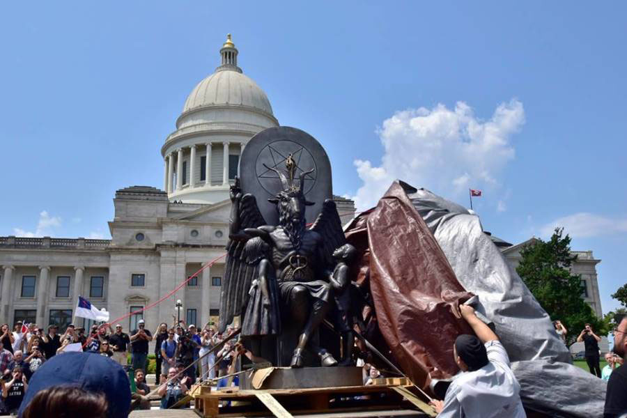 Satanic Temple members unveil their statue in protest for religious freedom. “This is not a protest against the Ten Commandments. This is a rally for reason in the face of prejudice, progress in the face of decline, liberty in the face of rising theocracy, and toleration in the face of infantile tribalisms,” Satanic Temple spokesman Lucien Greaves said. (photo from the Arkansas Times)