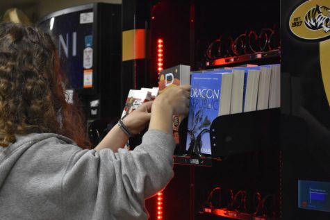 Junior Abby Swindler stocks the book vending machine. Books include authors Stephen King and Rupi Kaur.