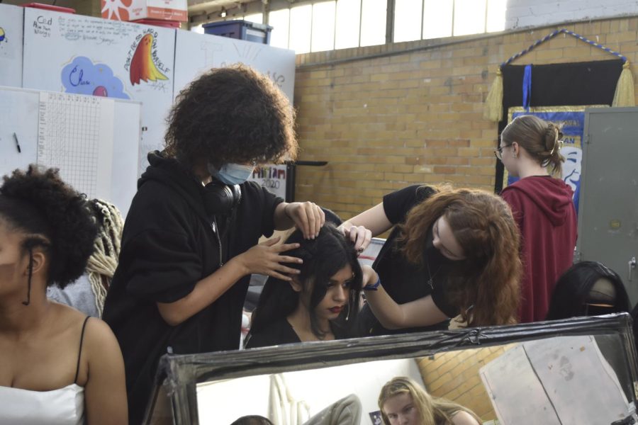 Kate Robinson and Rory McCuien help Lamis Vattoth place her wig as she practices lines to play Morticia in the play. 