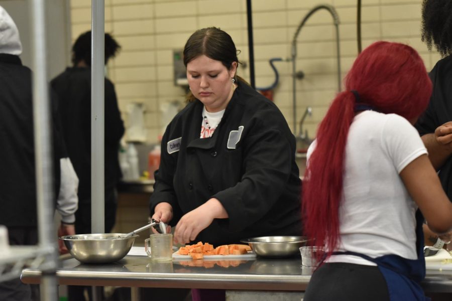 Junior, Samantha Calhoun slices yams on April 19, for her planned meal. 
