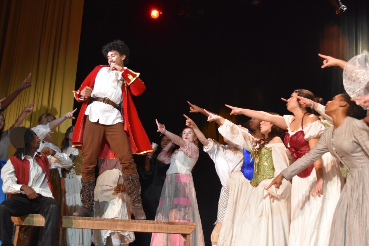 The cast of Beauty and the Beast points to freshman Keegan Washington. Washing plays main villain Gaston during the song Gaston on Nov. 2. 