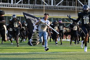 Senior, Jaden Carter leads football players onto the field to play the opening scrimmage against Jacksonville. The team won 9-0 Aug. 23. 
Photo by Chloe White