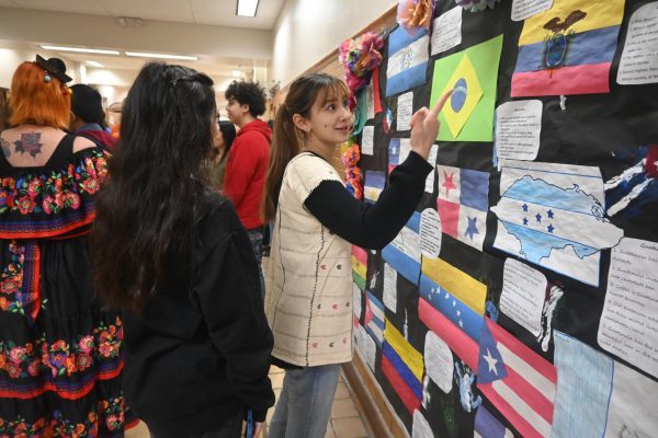 Sophomore Sophia Lager-Olarte points out the flags of different Spanish speaking countries as students gather for the Hispanic Heritage Parade. 