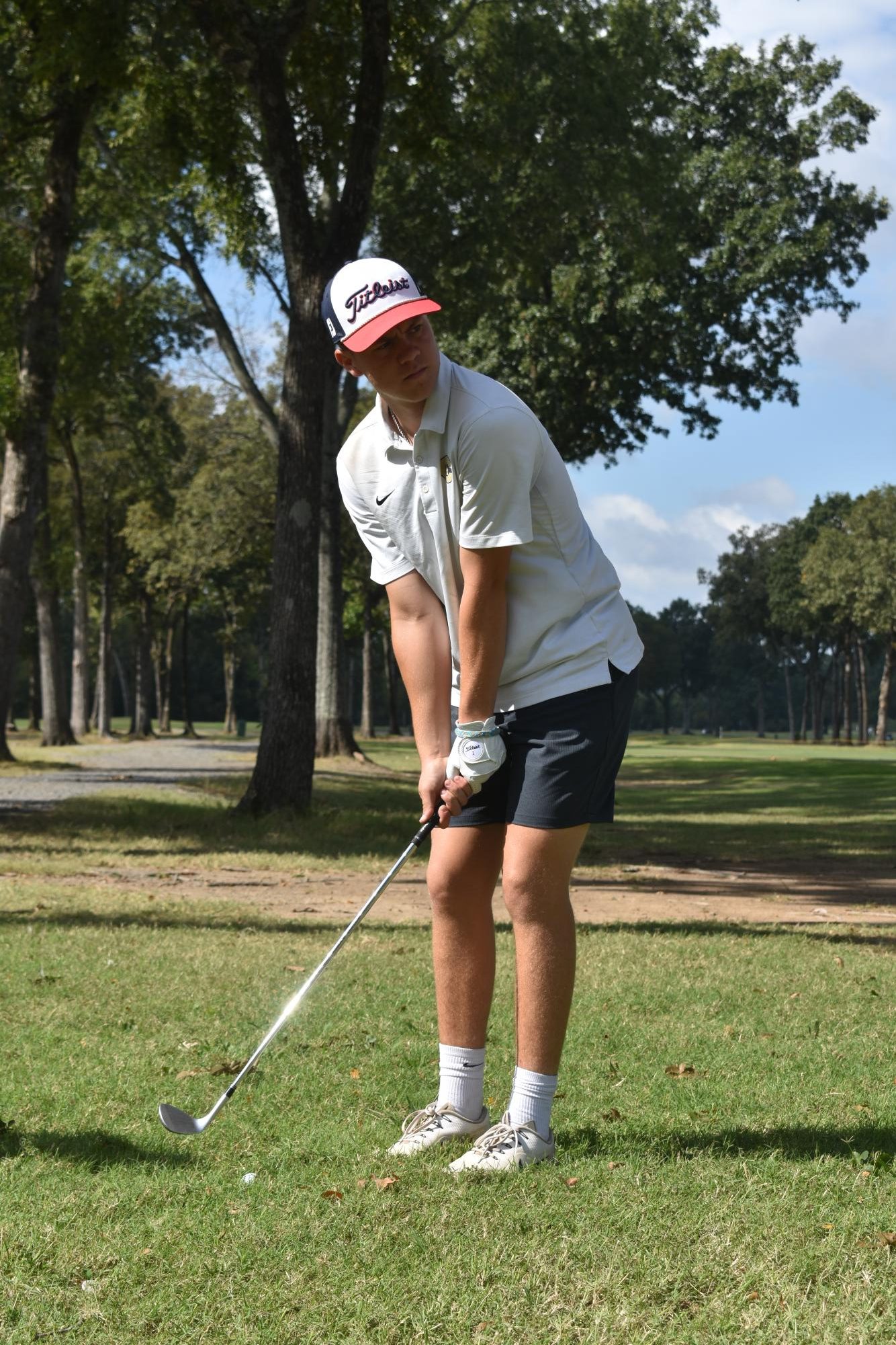Senior Fisher DeClerk hits a drive to the right of the fairway and sets up his next shot, trying to get pin high to a green 126 yards away.