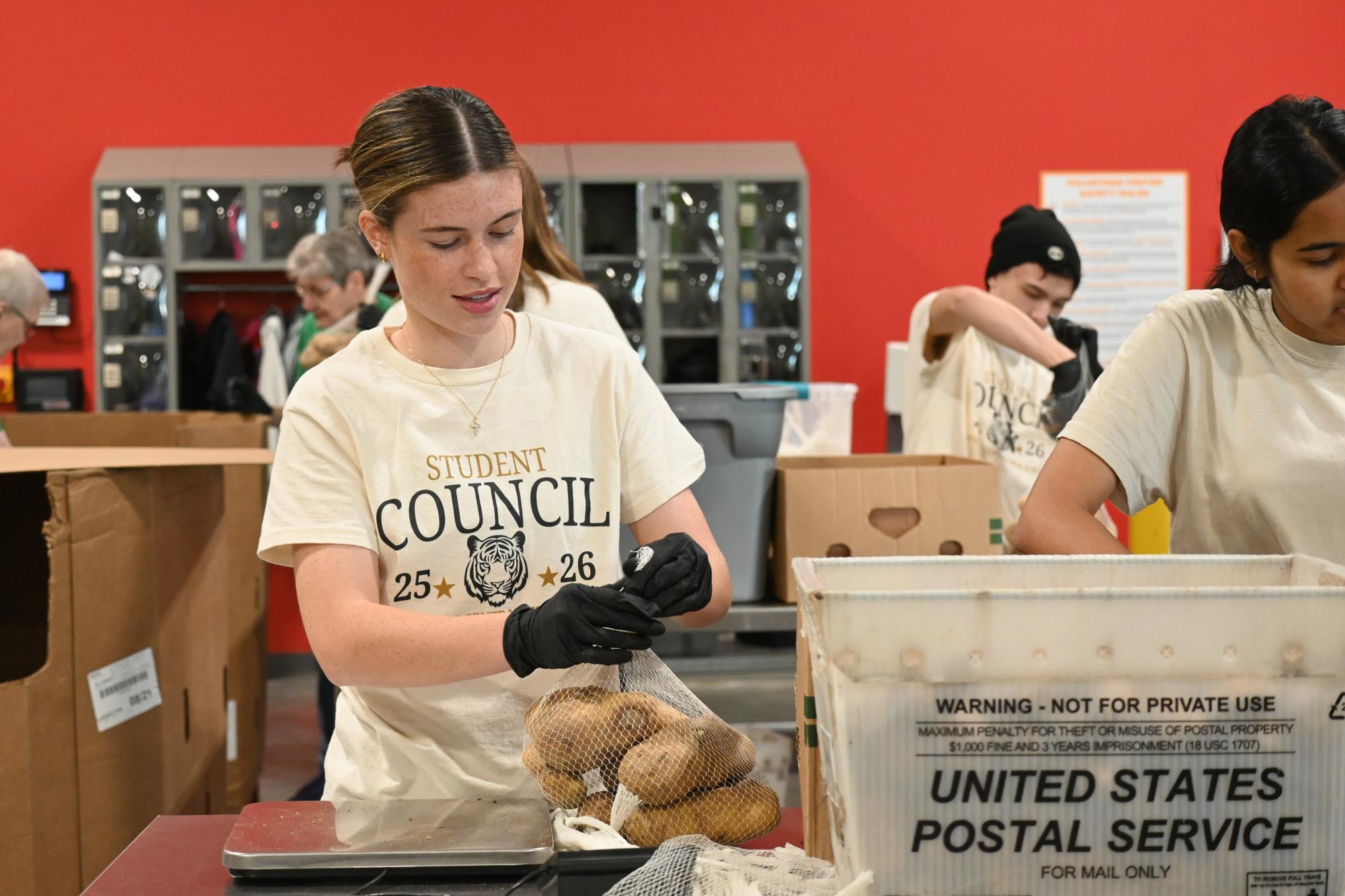 Junior Caroline Kolb weighs and ties potatoes to send to the community. 