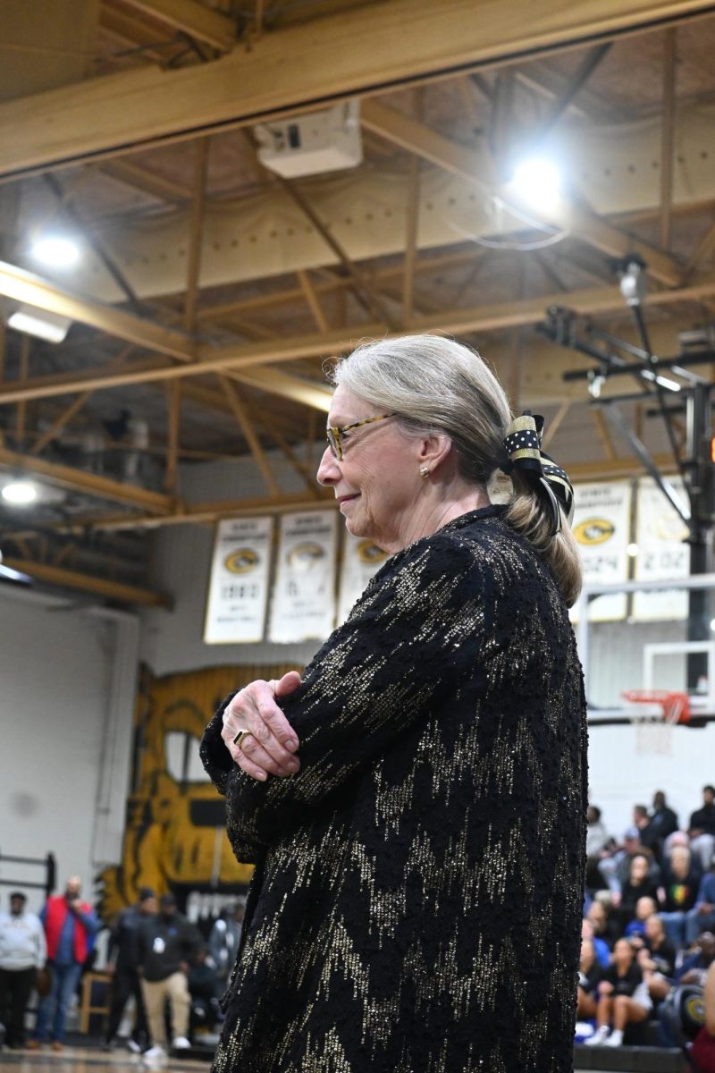 Principal Nancy Rousseau watches the homecoming court enter the gym at the homecoming basketball game, Feb. 20.