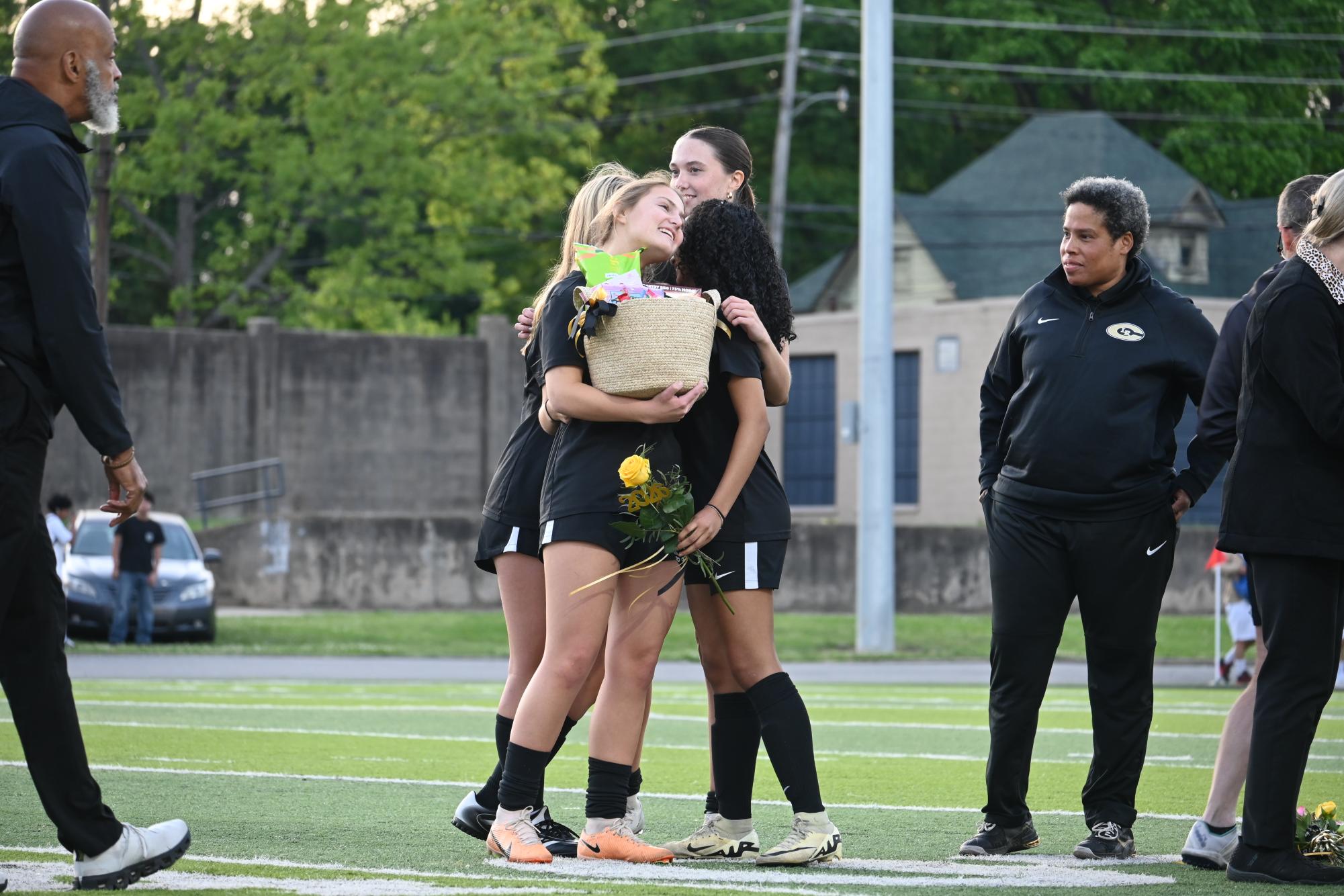 April 30, during Senior Night celebrations, senior Zora Gorrepati is presented her senior basket by sophomore Helen Teeter and juniors Helen Ferguson and Claire South.